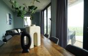 Comedor moderno con mesa de madera, jarrones únicos y vista a la terraza en Mode 6 lodge en De Achterhoek.