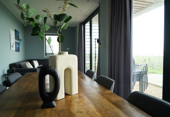 Moderne eetruimte met houten tafel, unieke vazen en uitzicht op terras in lodge Mode 6 in De Achterhoek.
