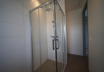 Moderne douchecabine met glazen deuren in Lodge Mode 6 bij De Achterhoek, Nederland, lichte tegels.