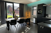 Moderne spise- og køkkenområde i Modus Sauna 4 lodge på De Achterhoek, Holland, med stort vindueudsigt.