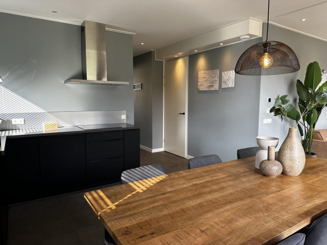 Modern lodge kitchen and dining area with wood table at Modus Sauna 4, De Achterhoek, the Netherlands.