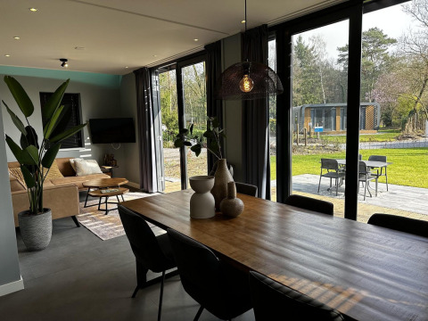Sala de estar y comedor moderno en Modus Sauna 4 en De Achterhoek, Países Bajos, con vista al jardín exterior.