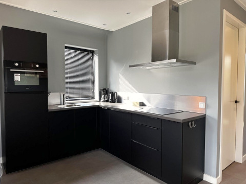 Moderne zwarte keuken in Modus Sauna 4, De Achterhoek, Nederland, met oven, afzuigkap en jaloezie.
