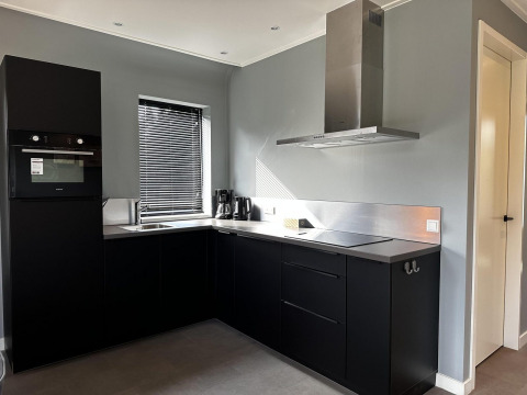 Cocina negra moderna en Modus Sauna 4, De Achterhoek, Países Bajos, con horno, campana y persianas.