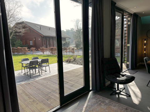 Uitzicht vanuit een moderne lodge met grote ramen op terras en tuin bij Modus Sauna 4, De Achterhoek, Nederland.