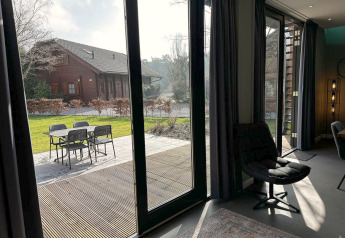 Uitzicht vanuit een moderne lodge met grote ramen op terras en tuin bij Modus Sauna 4, De Achterhoek, Nederland.