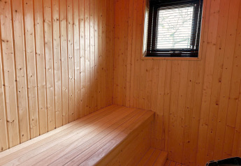 Houten interieur van Modus Sauna 4 bij De Achterhoek in Nederland, met bank en raam, warme sfeer.