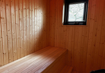 Houten binnenkant van Modus Sauna 4 te De Achterhoek in Nederland, met bankje en raam, rustgevende sfeer.