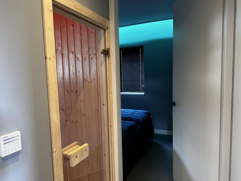 Indgang til et værelse med en træsaunadør og moderne soveværelse i Modus Sauna 4, De Achterhoek.