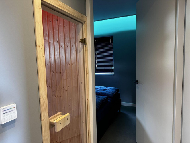 Entrada a una habitación con puerta de sauna de madera y dormitorio moderno en Modus Sauna 4, De Achterhoek.