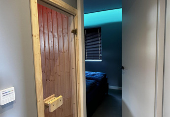 Entrada a una habitación con puerta de sauna de madera y dormitorio moderno en Modus Sauna 4, De Achterhoek.