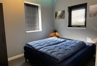 Modern ingerichte slaapkamer in Modus Sauna 4 bij De Achterhoek, Nederland, met tweepersoonsbed en blauwe dekbedden.