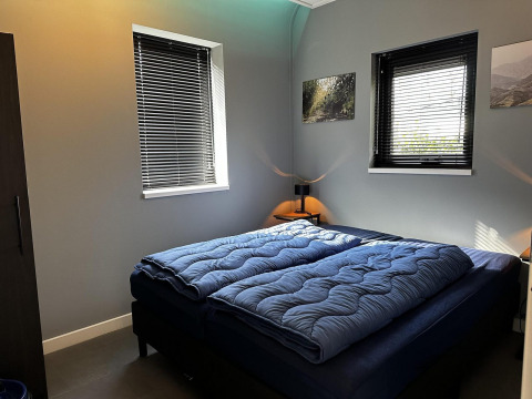 Moderne slaapkamer in Modus Sauna 4 bij De Achterhoek, Nederland, met dubbel bed en blauwe dekbedden.