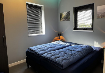 Moderne slaapkamer in Modus Sauna 4 bij De Achterhoek, Nederland, met dubbel bed en blauwe dekbedden.