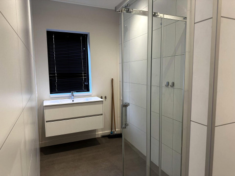 Moderne badkamer met witte wastafel, donkere jaloezieën en glazen douche in Modus Sauna 4, De Achterhoek, Nederland.