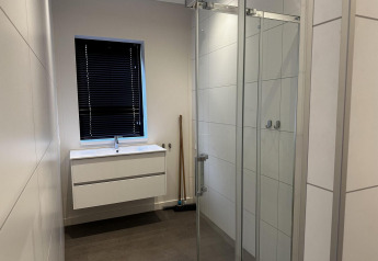Moderne badkamer met witte lavabo, donkere rolluiken en glazen douche in Modus Sauna 4, De Achterhoek, Nederland.