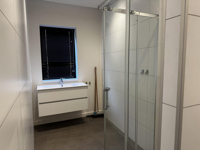 Modern bathroom with white sink, dark blinds, glass shower and tiled walls in Modus Sauna 4 at De Achterhoek, Netherlands.