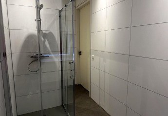 Moderne douche met glazen deuren in de badkamer van Modus Sauna 4, De Achterhoek, Nederland.