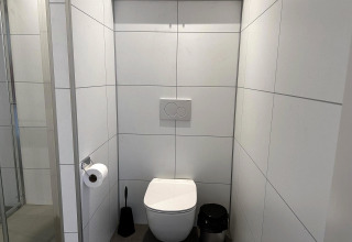 Modern toilet in Modus Sauna 4 bij De Achterhoek in Nederland, met witte betegelde muren.