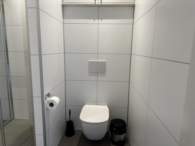 Modern toilet inside Modus Sauna 4 at De Achterhoek, Netherlands, featuring white tiled walls.