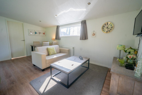 Helles Wohnzimmer im Pavilion 4 bei De Achterhoek, Niederlande, mit Sofa, Couchtisch und Uhr.