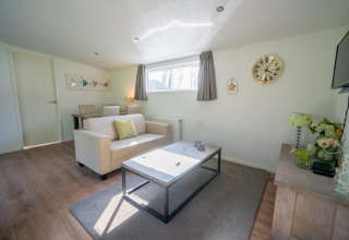 Helles Wohnzimmer im Pavilion 4 bei De Achterhoek, Niederlande, mit Sofa, Couchtisch und Uhr.