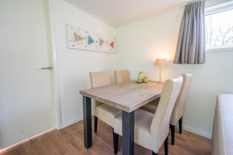 Essbereich im Pavilion 4 im De Achterhoek, Niederlande, mit Tisch, vier Stühlen, Lampe und Fenster.