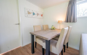 Essbereich im Pavilion 4 im De Achterhoek, Niederlande, mit Tisch, vier Stühlen, Lampe und Fenster.