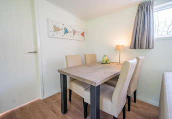 Eethoek in Pavilion 4 bij De Achterhoek, Nederland, met tafel, vier stoelen, kunstwerk en lamp.