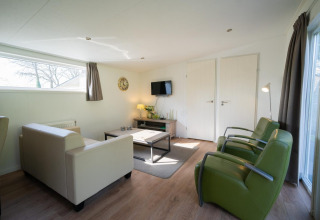 Modernes Wohnzimmer im Pavilion 4 in De Achterhoek, Niederlande, mit hellen Möbeln und grünen Sesseln.
