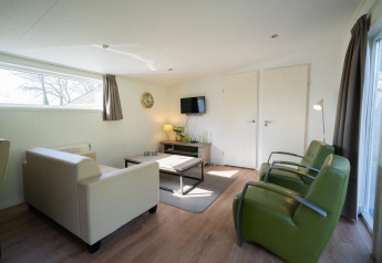 Moderne woonkamer in Pavilion 4 bij De Achterhoek, Nederland, met groene stoelen en lichte inrichting.