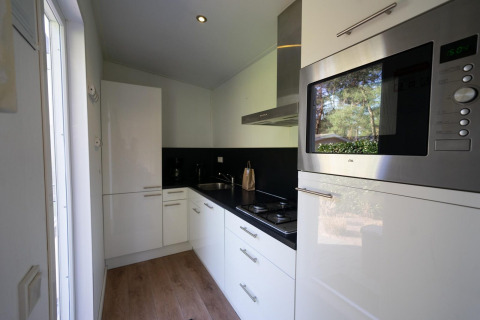 Moderne Küche im Pavilion 4 der De Achterhoek Lodge in den Niederlanden mit weißen Schränken und Geräten.