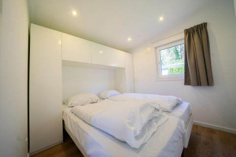 Dormitorio moderno en el Pavilion 4 de De Achterhoek, Países Bajos, con cama doble y mobiliario blanco.