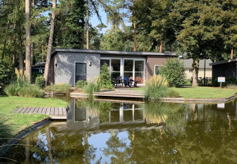 Pavillon 4 ved De Achterhoek i Holland, moderne lodge med terrasse og søudsigt omgivet af natur.
