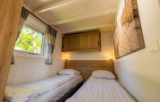 Slaapkamer met twee eenpersoonsbedden, houten kast en raam in Tiny House 4, De Achterhoek, Nederland.