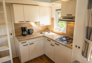 Kompakte, moderne Küche im Tiny House 4 bei De Achterhoek in den Niederlanden mit Gasherd und Kaffeemaschine.