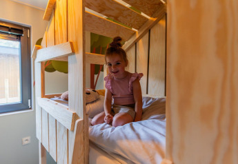Barn sidder på træseng i Kids cottage lodge ved Kaatsheuvel, Holland, i et hyggeligt børneværelse.