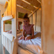 Barn sidder på træseng i Kids cottage lodge ved Kaatsheuvel, Holland, i et hyggeligt børneværelse.
