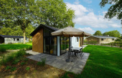 Moderna cabaña para bebés en Kaatsheuvel, Países Bajos, con terraza, sombrilla y césped verde.