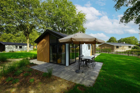 Moderna cabaña para bebés en Kaatsheuvel, Países Bajos, con terraza, sombrilla y césped verde.