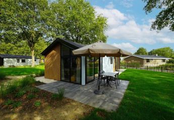 Modern babyhuisje in Kaatsheuvel, Nederland, met terras, parasol en groene gazon op een zonnige dag.