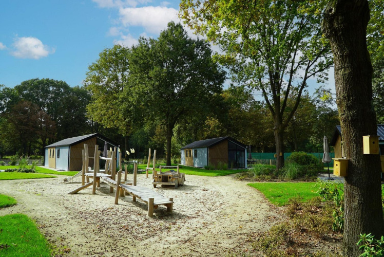 Parque infantil de arena y juegos de madera entre cabañas en Baby cottage, Kaatsheuvel, Países Bajos.