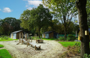 Parque infantil de arena y juegos de madera entre cabañas en Baby cottage, Kaatsheuvel, Países Bajos.