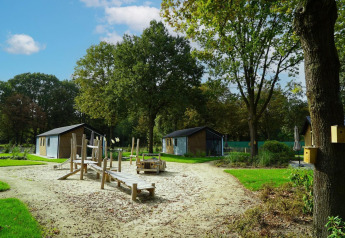 Parque infantil de arena y juegos de madera entre cabañas en Baby cottage, Kaatsheuvel, Países Bajos.