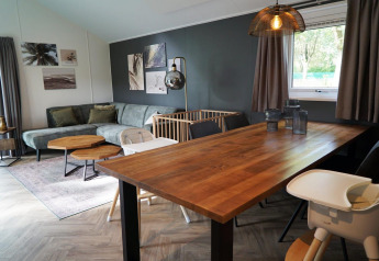 Moderne leefruimte in Baby cottage te Kaatsheuvel, Nederland, met eettafel, zetel en babybedje.
