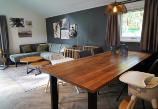 Moderne stue i Baby cottage i Kaatsheuvel, Holland, med spisebord, hjørnesofa og tremmeseng.