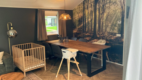Salle à manger du Baby cottage à Kaatsheuvel, Pays-Bas, avec lit bébé, table en bois et fresque forêt.