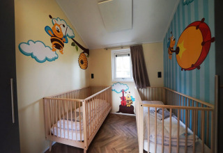 Stanza per bambini con due lettini e murales di api colorate al Baby Cottage a Kaatsheuvel, Paesi Bassi.