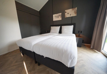 Moderne slaapkamer in Baby cottage lodge in Kaatsheuvel, Nederland, met twee eenpersoonsbedden en stijlvolle inrichting.