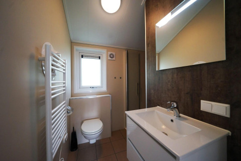 Salle de bain moderne avec lavabo, miroir, WC et radiateur dans un Baby cottage à Kaatsheuvel, Pays-Bas.
